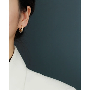 Close-up of elegant gold layered hoop earrings with zircon accents worn by a model
