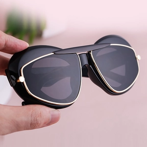 Detail of chunky black sunglasses with premium gold metallic trim on the cat-eye frame