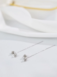 Macro shot of silver long tassel earrings with sparkling flower zircon details on silk