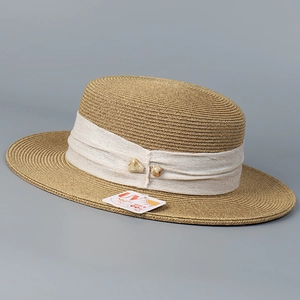 Detail of boater straw hat featuring white decorative band and UV 99% protection tag