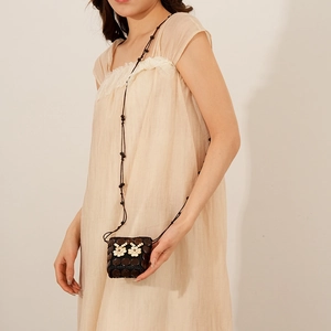Détail du sac à fleurs en coque de coco avec bandoulière perlée sur robe beige
