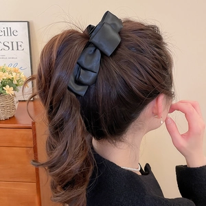 Détail d'une grande pince à cheveux nœud en similicuir noir portée par un mannequin