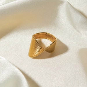Detail shot of 18k gold stainless steel twisted ring on white silk background
