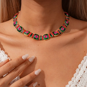 Gros plan d'un collier géométrique en émail vert et rose sur un modèle féminin