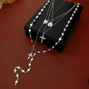 Detail of silver rosary necklace with white pearls and cross on black gift box