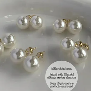 Classic round creamy white pearl earrings with 18k gold needles in a ceramic tray