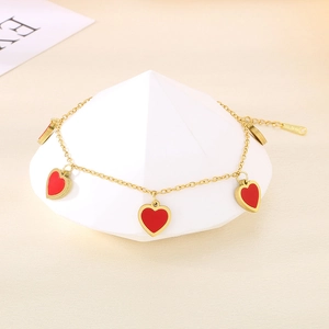 Dettaglio di ciondoli a cuore rosso su catena in acciaio placcato oro 18K con logo