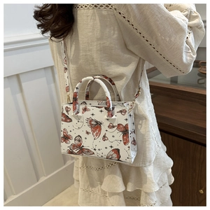 Sac bandoulière tendance avec imprimé papillon porté par un mannequin en intérieur