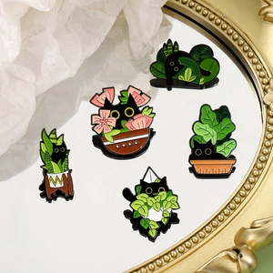 Set of five cute black cat enamel pins with green indoor plants on a mirror surface