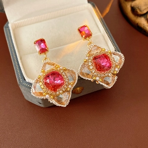Macro detail of vintage floral pearl earrings with magenta gems in a luxury velvet gift box