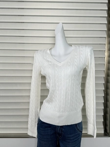 Close-up of white V-neck cable-knit sweater texture with ribbed cuffs and hem detail
