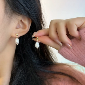 Close-up of elegant baroque freshwater pearl earrings with gold stud on a model