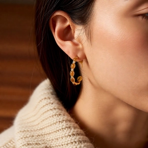 Gros plan de boucles d'oreilles en C plaquées or 18k avec pierres ambrées et cristaux