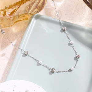 Silver chain necklace with white pearls and sparkling pavé crystal spheres in a blue tray