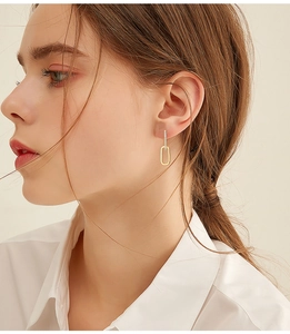 Close-up of elegant gold rectangular earrings with moissanite crystals worn by a model