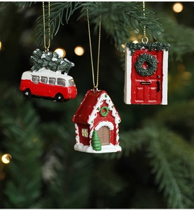 Close-up of red resin Christmas tree ornaments including a van and house on pine branches