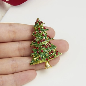 Detailed view of gold Christmas tree brooch with green enamel and sparkling red rhinestones