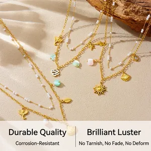 Detail of layered gold necklaces with sea stars, pearls, and shells on beach sand