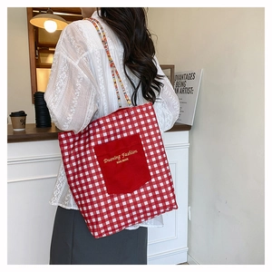 Detalle del bolso tote de lona a cuadros rojos y blancos con correa tejida y bolsillo