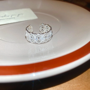 Detailed view of silver lace flower ring with cubic zirconia on a decorative plate