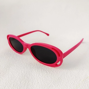 Detail view of stylish rose pink square sunglasses with dark lenses on textured surface