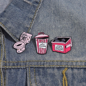 Lot de pins émaillés roses avec motifs de toilettes et poubelles sur veste en jean