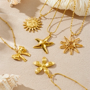 Gold plated necklaces with starfish, flower, and sun charms on a beach-themed backdrop