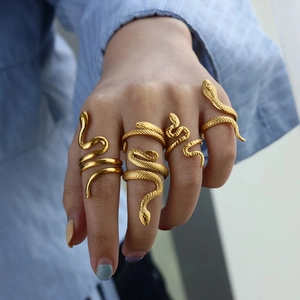 Close-up of four gold snake rings with scale textures on a model's hand