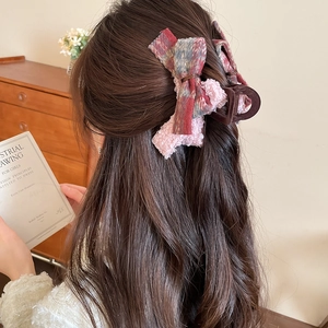 Detailed back view of a model wearing a pink flocked bow hair claw clip in a cozy home setting