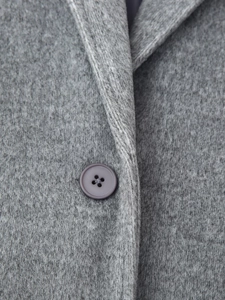 Macro shot of grey wool fabric texture and button detail on a minimalist winter coat