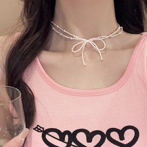 Gros plan d'un collier double rang en perles avec un pendentif nœud papillon en acrylique