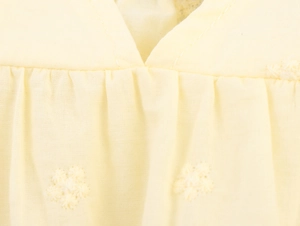 Close-up of yellow poplin top with delicate floral embroidery and pleated V-neckline