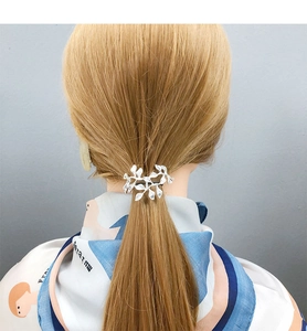 Close-up of a silver leaf-shaped metal hair hook accessory styled on a low ponytail