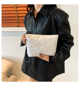 White textured floral fabric clutch bag held by model wearing a black shirt