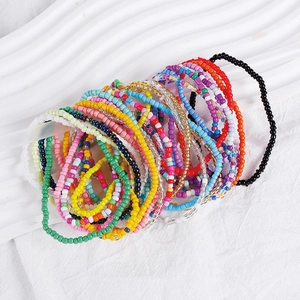 Detail of colorful bohemian seed bead bracelets stacked on a white wavy display tray