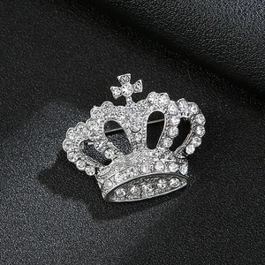 Macro shot of silver crown brooch with white rhinestones and cross on leather background