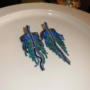 Macro detail of leaf-shaped rhinestone tassel earrings with blue and green gradients