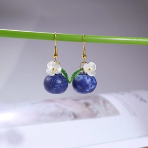 Close-up of blueberry dangle earrings with white flowers and green leaves on gold hooks