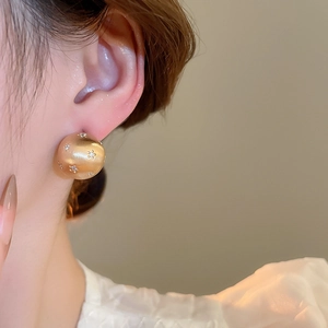 Close-up of 18k gold plated brushed spherical stud earring with starburst zircon inlay