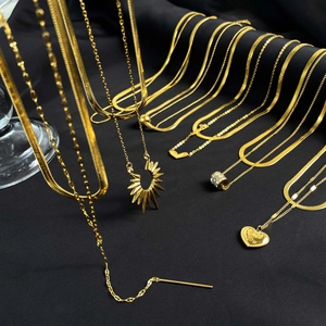 Layered 18K gold plated heart and cylinder necklaces displayed on black fabric