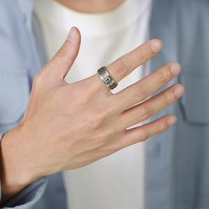 Close-up of a silver stainless steel spinner ring with engraved Christian scripture on a hand
