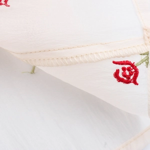 Floral embroidery detail on a cream backless halter maxi dress with delicate stitching