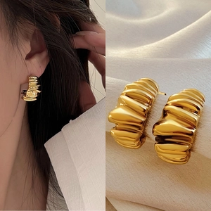 Macro detail and model view of C-shaped 18k gold croissant earrings with pleated texture