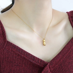 Detailed close-up of 18K gold minimalist female body art pendant on a fine link chain