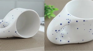 Detail of white ceramic mug with blue ink splatters and unique thick handle on placemat