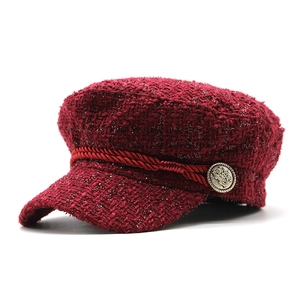 Detail of burgundy tweed newsboy cap featuring metallic threads and gold crest button