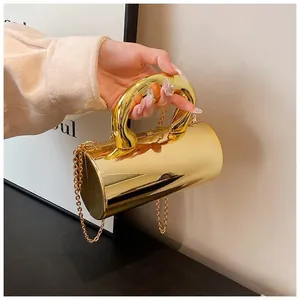 Detail of a cylindrical gold hardshell evening clutch with a thick top handle and chain strap