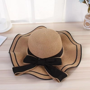 Detailed close-up of a khaki straw sun hat with black wavy edge and ribbon bow