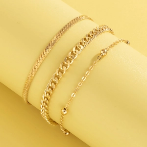 Close-up of golden three-piece bracelet set with snake, cuban and bead chain detail