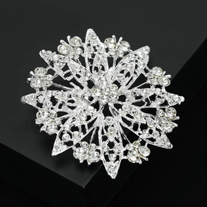 Macro shot of silver sunflower brooch featuring sparkling crystals on a black surface